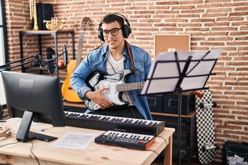 Young man artist playing electrical guitar at music studio