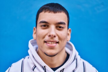 Young man smiling confident standing over blue background