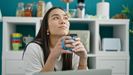 Young beautiful hispanic woman drinking coffee sitting on table at dinning room