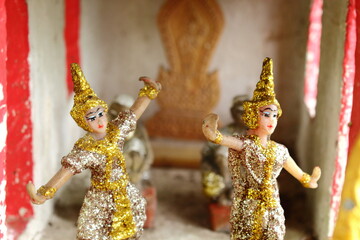 Close up of two Thai folk dancer doll in the spirit house with blur background.