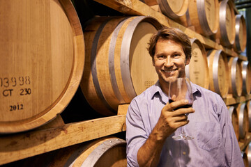 Portrait, smile and wine tasting with a man in the cellar of a distillery on a farm for the...