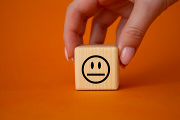 Neutral smile symbol. Neutral smile on wooden cubes. Businessman hand. Beautiful orange background. Business and Neutral smile concept. Copy space.