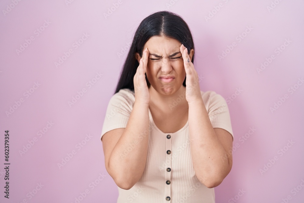 Canvas Prints Young hispanic woman standing over pink background with hand on head, headache because stress. suffering migraine.