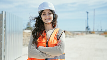 Young beautiful hispanic woman builder smiling confident standing with arms crossed gesture at street