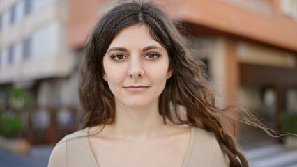 Young beautiful hispanic woman standing with serious expression at street