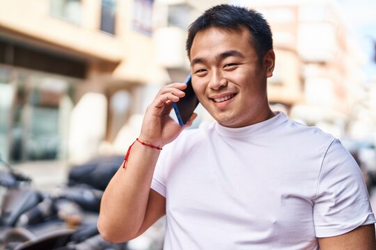 Young chinese man smiling confident talking on the smartphone at street