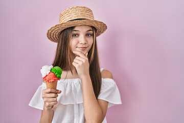 Teenager girl holding ice cream looking confident at the camera smiling with crossed arms and hand...