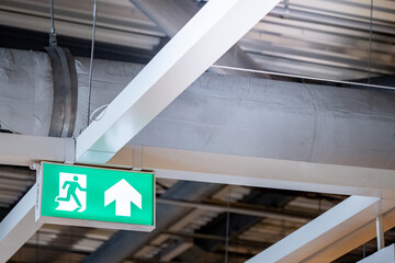 Green emergency fire exit sign showing the way to escape with an arrow symbol.