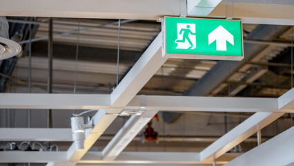 Fototapeta premium Green emergency fire exit sign showing the way to escape with an arrow symbol.