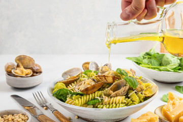 Pouring olive oil in seafood pasta with clams vongole, parmesan cheese, spinach, pine nuts. Italian food
