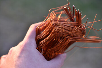 Fototapeta na wymiar A bundle of copper wire in his hand. Copper scrap. Shiny red copper wire.