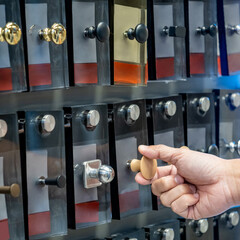 Male hand choosing cabinet door knob from hardware material display in furniture store. Home...