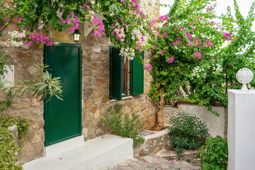 Beautiful courtyard of an old brick house in old town with blooming pink flowers of bougainvillea. Travel, vacation concept. European architecture