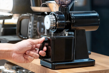Buying coffee maker equipment. Male hand holding black coffee grinder machine in barista tool shop.