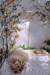 A bed in a bright bedroom surrounded by plants and flowers. The concept of good morning and fresh air like in the forest, air purification and air humidification, healthy lifestyle.