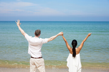 back couple holding hands and looking to sky on the sea