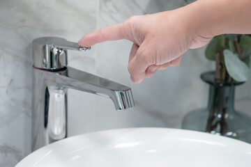 Save water concept. Hand closing stainless steel water tap or chrome faucet in the bathroom.