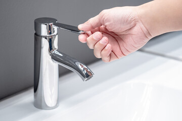 Save water concept. Hand closing stainless steel water tap or chrome faucet in the bathroom.