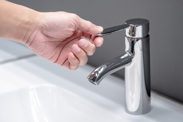 Save water concept. Hand closing stainless steel water tap or chrome faucet in the bathroom.