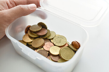 Euro cent coins in a plastic box.  Hand opening a box with Euro cent coins in it. 