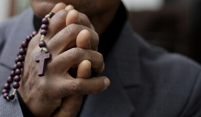 man praying to god with hands together Caribbean man praying with grey background stock photos stock photo