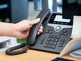 Call center and customer support. Operator hand trying to response customer call by using landline...