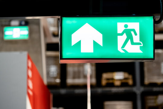 Emergency exit sign or fire exit sign hanging on rack structure in warehouse