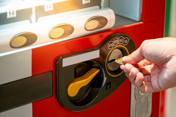 Male hand putting coin into cold drink and snack elevator vending machine.