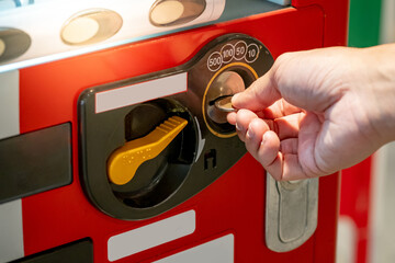 Male hand putting coin into cold drink and snack elevator vending machine.