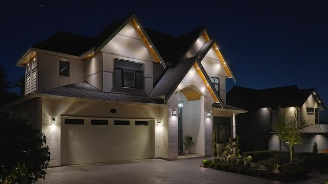 Establishing shot of two story stucco luxury house with garage door, big tree and nice landscape at night in Vancouver, Canada, North America. Night time on Apr 2023. ProRes 422 HQ.