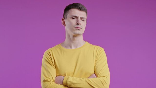 Offended young man, arms crossed, feeling mad. Teen maximalism. Pink background.