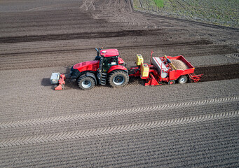 Luftbild - Seitenansicht von oben, moderne Landtechnik bei der Kartoffelpflanzung - Roter Traktor...