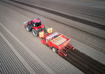 Drohnenfoto - Traktor mit Kartoffellegemaschine beim legen von Saatkartoffeln, die Kartoffeldämme...