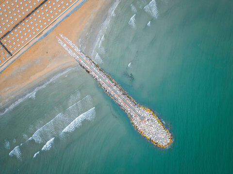 Smooth sea with beach and leaden rocks. Late spring, cloudy skies and rain to come. Italy, Veneto, shore of Eraclea. Sun.