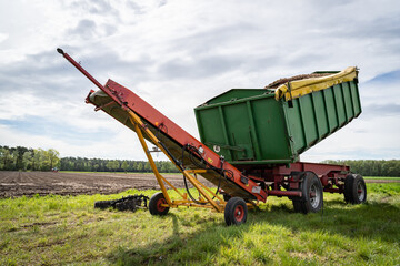 Obraz premium Anhänger mit Pflanzkartoffeln und ein Förderband zum Befüllen der Sämaschine.