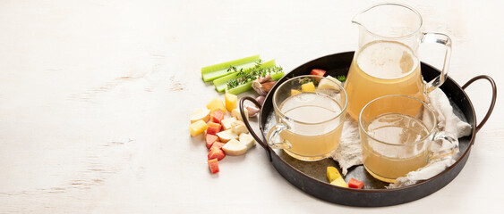 Glass jar with yellow fresh bone broth on white background. Healthy low-calories food is rich in vitamins, collagen and anti-inflammatory amino acids.