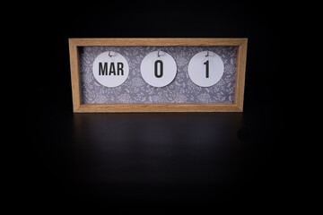 A wooden calendar block showing the date March 1st on a dark black background, save the date or date of event concept.