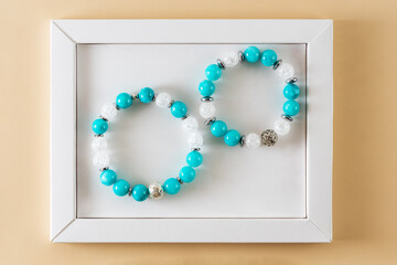 two amazonite bracelets in a white frame on a beige background. space for copying.