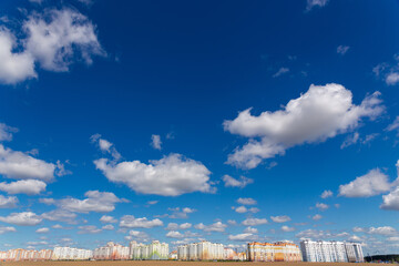 Fototapeta na wymiar Deep blue skies with white clouds background and modern multi-storey residential area on the horizon