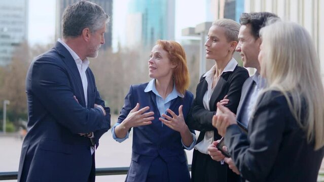 Mature boss talking with a team of business people outdoors