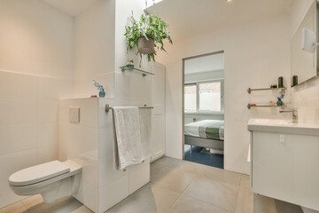 a bathroom with a toilet, sink, and plant in the center of the room on the right is an open shower stall