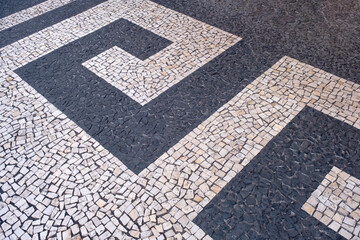 Fototapeta premium Traditional design on cobblestone sidewalk, Funchal, Madeira island, Portugal. Black and white mosaic floor from calcada tiling.