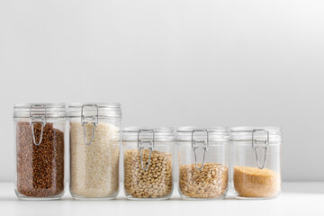 food, healthy eating and diet concept - jars with buckwheat, rice, oat flakes, couscous and beans...