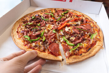 pizza with veggies and Salami with a hand