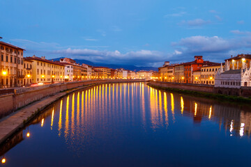 Panoramic view of the old town of Pisa and the Arno river at twilight, Italy. Night cityscape