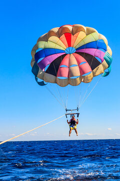 Parasailing water amusement - flying on a parachute behind a boat on a summer holiday by the sea. Summer vacation concept
