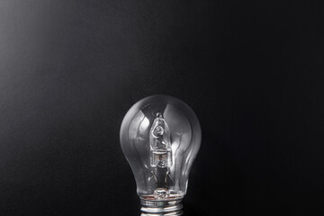 electricity, energy and power consumption concept - close up of lightbulb on black background
