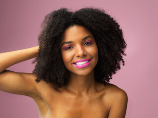 Face, hair care and happy black woman with makeup in studio isolated on a pink background with eyeshadow. Hairstyle portrait, lipstick cosmetics and African female model with salon treatment for afro