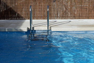 Swimming pool with metal ladder outside in internal yard of the condo in Madrid, Spain. Clean water...