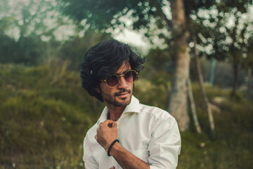 Portrait of a Handsome Indian man with long hair wearing sunglasses in White Shirt